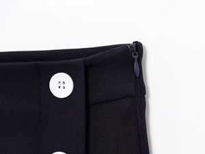 Dettaglio della vita di una gonna in twill blu navy con bottone bianco e zip invisibile