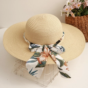 Détail d'un chapeau de paille à large bord avec ruban floral et décorations en perles