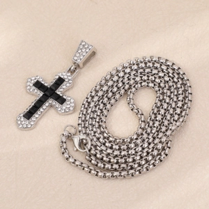 Detailed shot of silver cross pendant with black gems and sparkling crystals on chain
