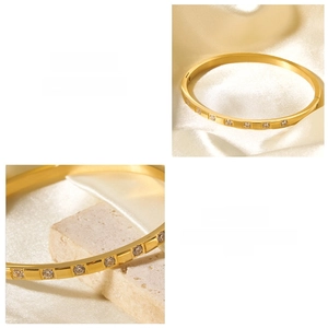 Detail of 18k gold plated bangle featuring inlaid white zircons on pearl satin background