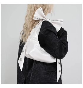 Detailaufnahme der weißen Lackleder-Tragetasche mit Nieten-Schleifen-Design