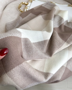 Detailed close-up of brown and beige plaid knit scarf fabric with soft wool-like texture
