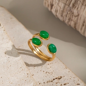 Bague ajustable dorée avec trois pierres de turquoise verte sur fond de pierre