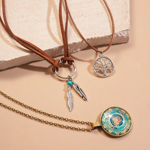 Detail of three-piece bohemian necklaces featuring tree of life and feather pendants