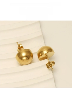 Detail of gold dome stud earrings in polished stainless steel on a white wavy pedestal