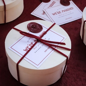 Detail of white wedding favor box with burgundy velvet ribbon and wax seal decoration