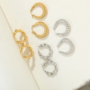 Detailansicht strukturierter Creolen in Gold und Silber mit gedrehtem und geometrischem Stil