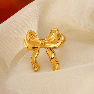 Polished 18K gold plated stainless steel bow ring on elegant white satin fabric