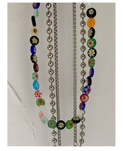 Détail macro de perles en verre Millefiori colorées et de colliers en argent superposés