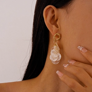 Close-up of bohemian gold earrings with dangling shell discs worn by a model