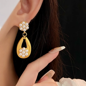 Detail of vintage gold flower and teardrop earrings with pearls on a model