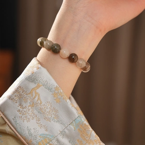 Détail d'un bracelet en perles de quartz colorées porté sur un vêtement brodé