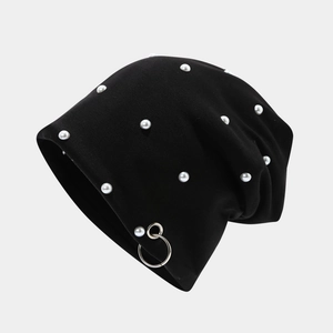 Detail view of black knit beanie featuring white pearls and a silver metal ring accent