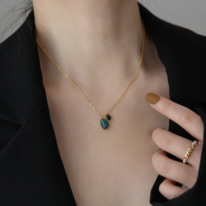 Elegant gold necklace with green and black pendants and pearl ring on model