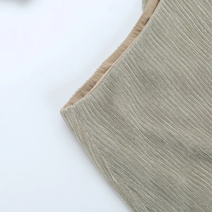 Close-up of champagne gold metallic pleated fabric and detailed stitching on the dress