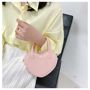 Pink heart-shaped jelly shoulder bag styled with a white pleated skirt and yellow shirt