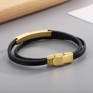 Detail of double-layer black leather bracelet with matte gold metal clasp and hardware