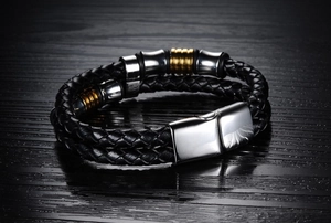 Close-up of black braided leather bracelet with gold accents and silver magnetic clasp