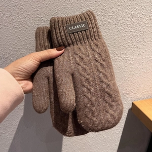 Dettaglio di muffole marroni in maglia da uomo con motivo a trecce e polsini a coste
