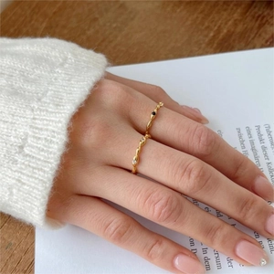 Detailed close-up of a slim gold sterling silver ring with zircon on a model's hand