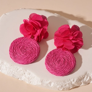 Detail of rose pink fabric flower earrings with woven raffia geometric circle drops