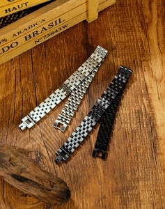 Detailed view of silver and black stainless steel watch bands on a vintage wooden surface