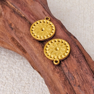 Two golden stainless steel sunburst circle pendants on rustic wood and linen background