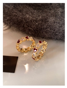 Detailed close-up of gold plated hoop earrings with red enamel hearts and zircon stones