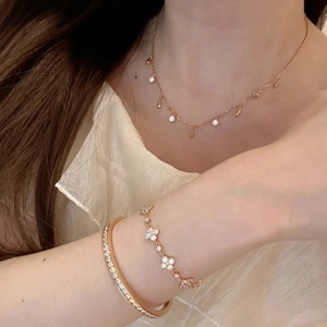 Detail of rose gold jewelry set with clover bracelet and shimmering crystal pendant