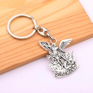 Detailed close-up of Saint Michael silver pendant keychain on a light wood background
