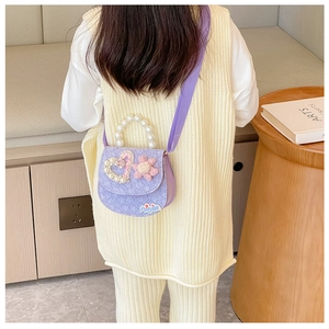 Close-up of child model wearing a lavender lace crossbody bag with pearl handle