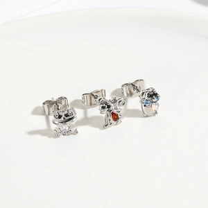 Detailed view of silver animal stud earrings with colorful zircon stones on ceramic plate