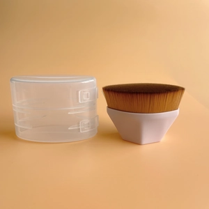 Flat foundation brush with dense brown bristles and hexagonal white handle in clear storage case