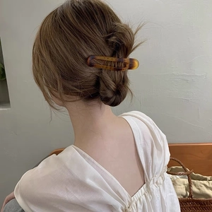 Detailed back view of a woman wearing a matte amber tortoiseshell claw clip for hair styling