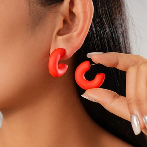 Detailed close-up of dark red matte acrylic C-shaped earrings worn by a female model
