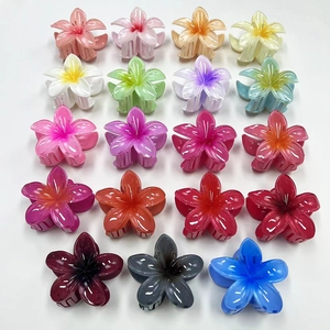Flat lay showing nineteen assorted gradient color frangipani flower hair claw clips