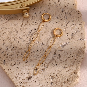 Detail view of 18K gold plated long link chain earrings on a textured stone surface