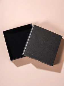 Top view of a square charcoal grey gift box with textured paper finish and lid askew