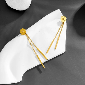 Elegant gold daisy stud earrings with long metal tassels on a minimalist display stand