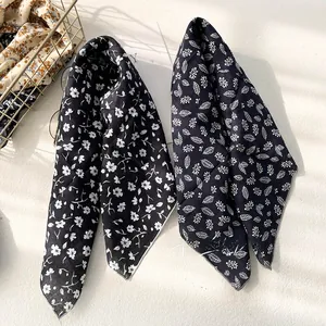 Detailed view of floral and leaf print scarves with high-quality stitched edges