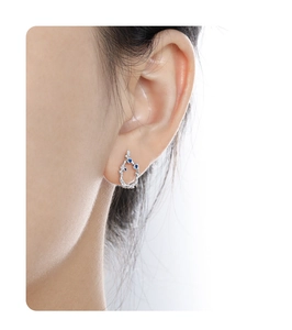 Macro shot of silver lava branch earrings with three blue gemstones worn on ear