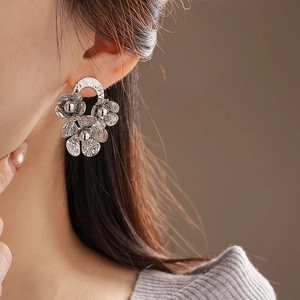 Close-up of elegant pleated flower stud earrings in silver on a model's ear