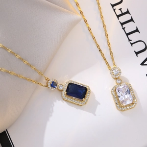 Close-up of gold-plated necklaces with emerald-cut blue and white zircon pendants