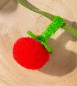 Macro shot of handmade red persimmon catnip toy in soft wool felt with green leaves