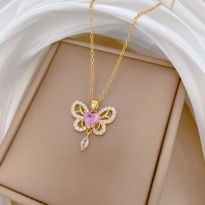 Macro view of gold butterfly pendant with pink heart stone and sparkling crystals