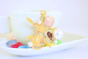 Detail of a gold starfish keychain with pearls, colorful rhinestones and shells