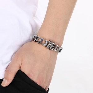 Close-up of a chunky silver stainless steel Cuban link bracelet on a male model wrist