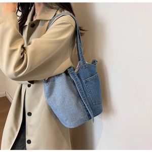 Detail of vintage denim bucket bag with patchwork design and practical exterior pocket