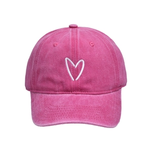 Detail der weißen Herzbestickung auf dem gewaschenen Baumwollstoff der rosa Baseballkappe