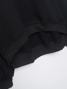 Primer plano del dobladillo y puños acanalados de sudadera negra con costuras finas
